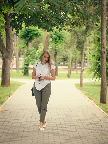一位穿着白衬衫的美女在公园里散步。图片下载