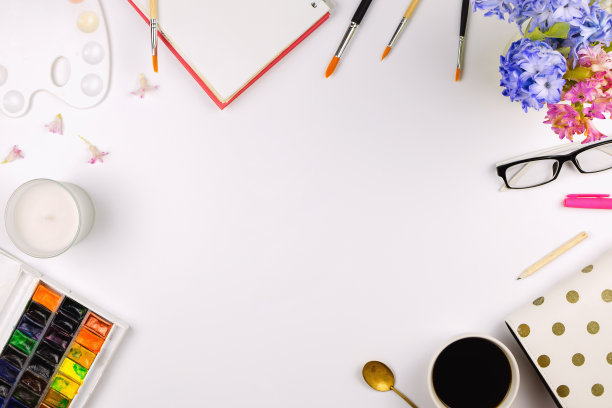 平铺配有艺术用品、鲜花、玻璃杯、咖啡杯等配件，创意工作空间概念。白色背景图片下载