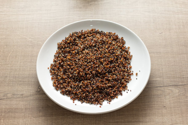 煮红和黑藜麦混合。白色的盘子和木制的桌子上用餐。图片下载