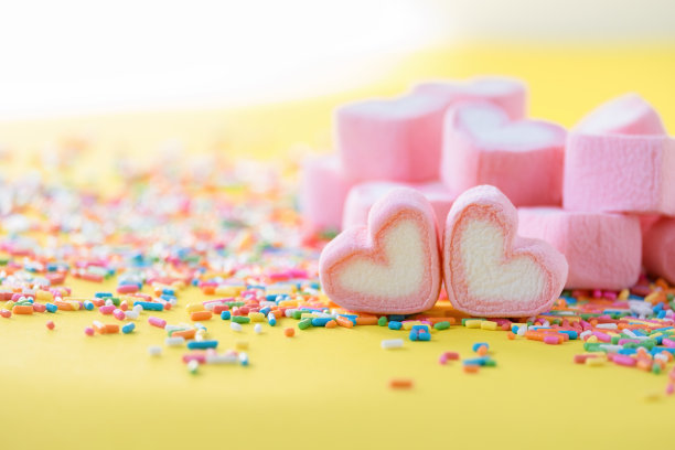 心形的粉红色棉花糖，点缀在绿色的背景和复制空间。情人节爱情庆祝的概念。图片下载