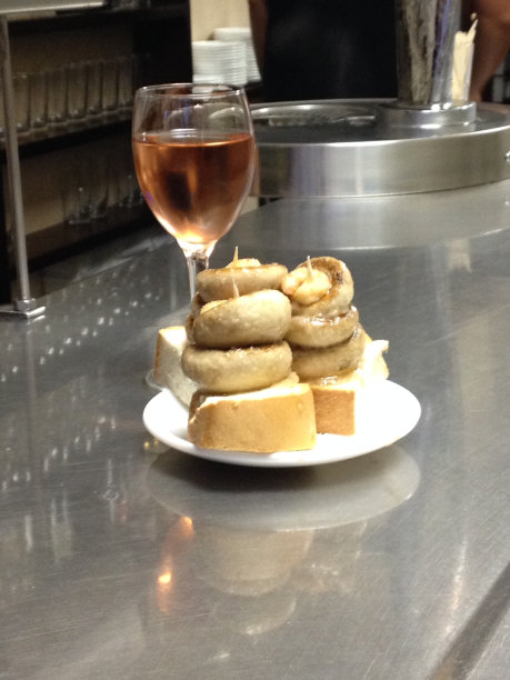 西班牙小吃包括一杯红酒和一小盘两片面包，每片面包上放着三片炸蘑菇图片下载