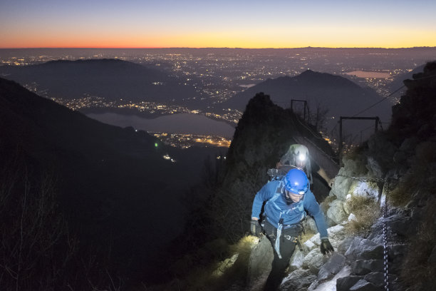 黄昏时分，城市上空山上的徒步旅行者图片下载