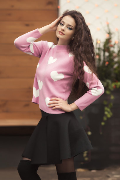 肖像年轻时尚的卷发女人独自在可爱的套头衫与心图片下载