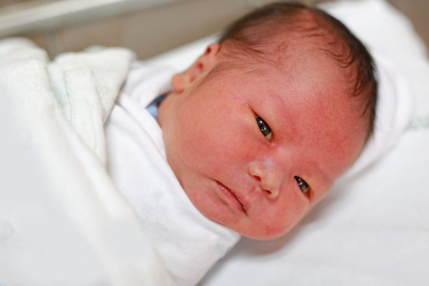 亚洲婴儿的特写脸在毛毯看着相机。图片下载