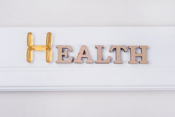 维生素E补充剂。健康这个词是抽象的木制字母和鱼油胶囊。图片下载