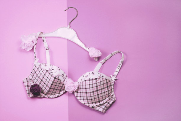 文胸挂在衣架上，粉色背景图片下载