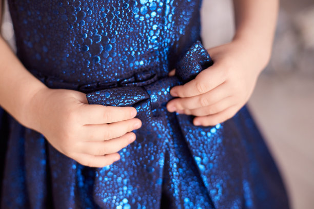 蓝色的裙子。伟大的弓。儿童的手。水平图片下载