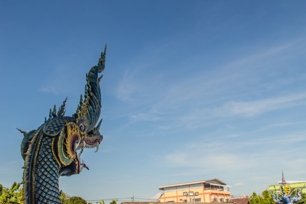 在阳光明媚的日子里，美丽的蓝色那迦雕塑，蓝天白云，在泰国清莱的公共寺庙，Wat Rong Sua Ten。那伽是一种非常大的蛇，在佛教寺庙中可以找到。图片下载