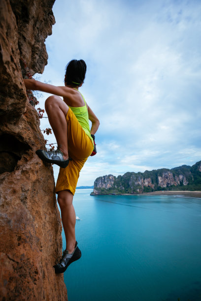 女攀岩者在海边悬崖上攀岩图片下载