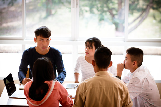 亚洲学院的学生小组使用笔记本电脑，平板电脑，一起学习笔记本文件纸和图表在课堂上报告。青年学习计划的学习任务，教育理念图片下载