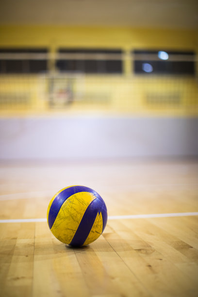 一个排球放在体育馆的木地板上图片下载