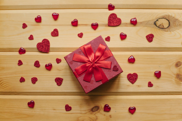 一份礼物装在一个漂亮的吊车盒子里，用丝带系在一个木制的表面上。图片下载