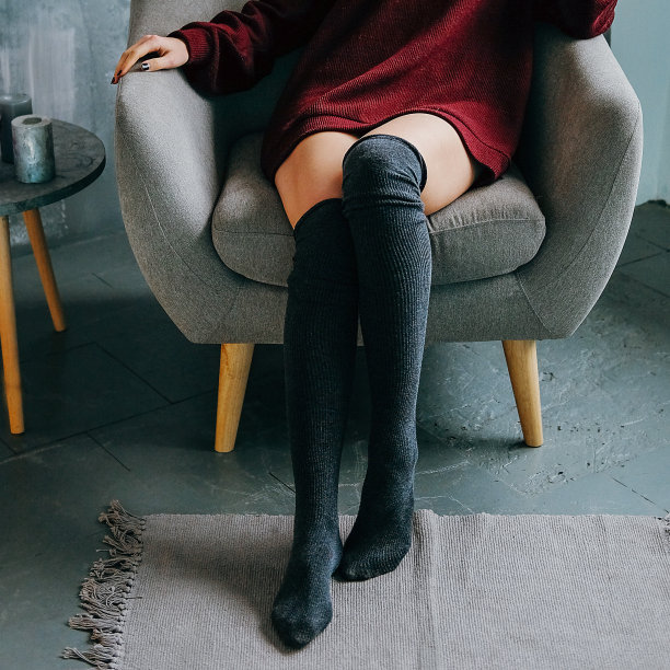 年轻的成年人轻松的女人在波尔多毛衣和膝袜休闲装坐在灰色扶手椅在极简主义现代室内图片下载