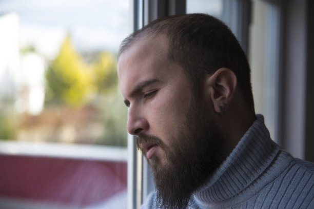 站在窗边悲伤愤怒的年轻人图片下载