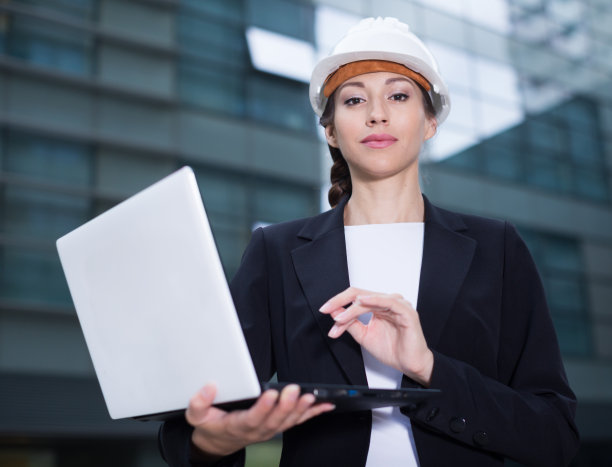 微笑的女工程师在西装和帽子与文件夹是探索项目在他的笔记本电脑图片下载