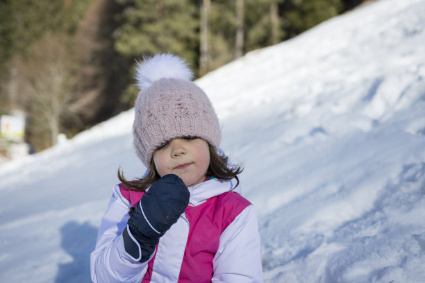 一个可爱的小女孩正在冬天的树林里吃雪。复制负空间。图片下载