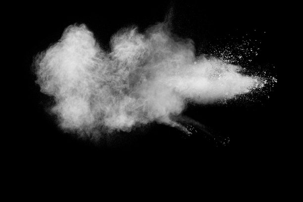 在黑色背景上发射白色粒子飞溅。在黑暗的背景下出现了奇异的白色粉末爆炸云。图片下载