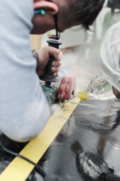 工匠用角磨床切割石板，用水射流冷却图片下载