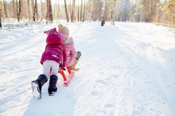 女孩推着雪橇，与妹妹一起骑车素材图片