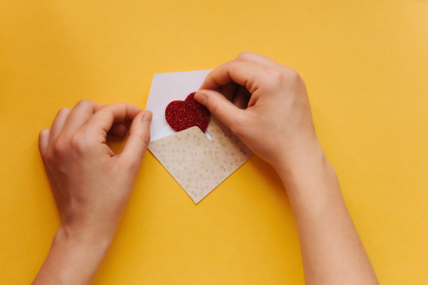 女孩写了一封祝贺信，并在信封上贴了一个心形的符号。图片下载