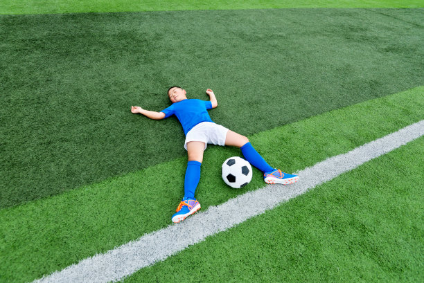小男孩躺在足球场上素材图片