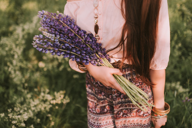 肖像年轻的棕色头发的女性模特与一束紫色的花在手里图片下载