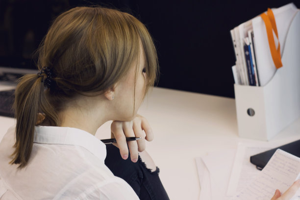 手持钢笔阅读笔记本上文字的年轻女人图片下载