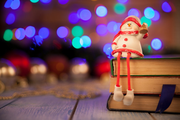 一个雪人拿着一个铃铛，坐在一本书上，在一个散糕前图片下载