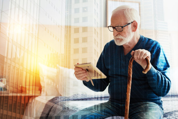 平静的老人坐在那里，看着他手中的照片图片下载