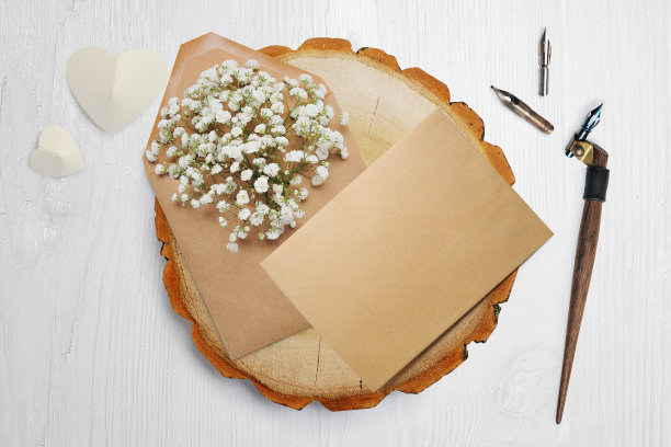 一根书法羽毛，躺在一个木圈旁边，上面有一颗白纸做的心。情人节贺卡上有你的文字。平躺，俯视图照片模拟图片下载