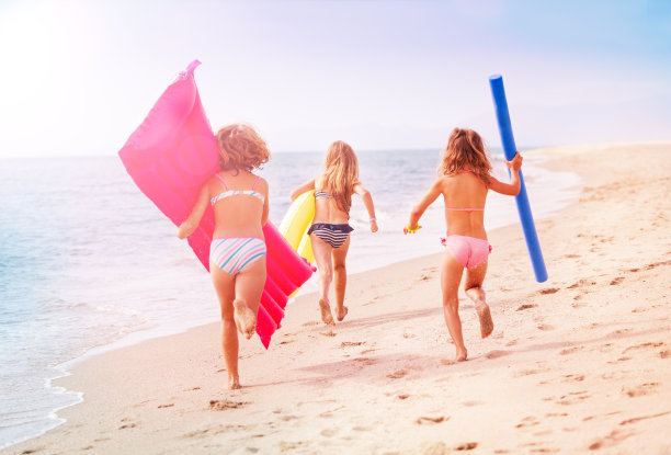 女孩们拿着游泳工具在海边跑步图片下载