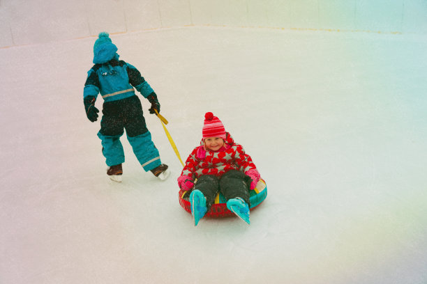 小男孩滑板推快乐的姐姐在管，孩子们冬天的乐趣图片下载