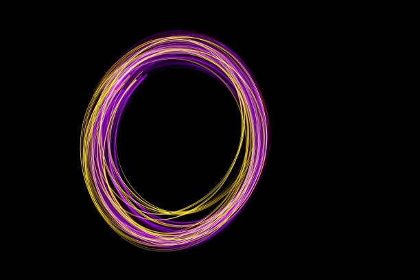 粉色和金色的光画摄影，光线在一个圆圈图案，长曝光照片，以黑色为背景图片下载