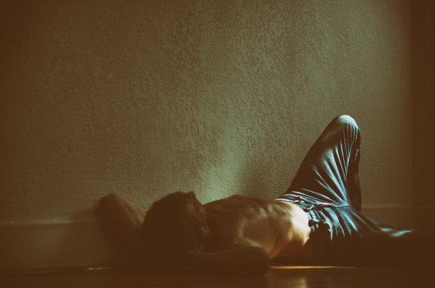 赤裸上身的男人躺在深色的木地板上图片下载