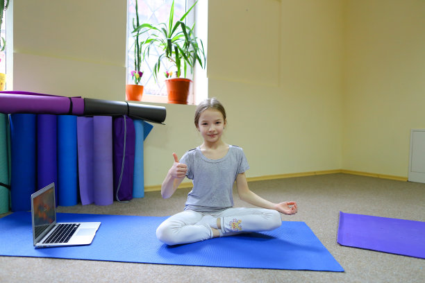 小女孩以莲花坐姿坐在地板上图片下载