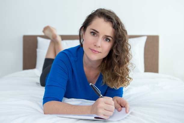 严肃的白人女人躺在床上写笔记图片下载
