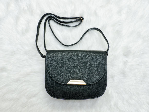 白色皮草上的黑色手提包。时尚的概念图片下载