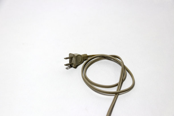 用奶油色的插头和电缆放在白色地板上。用于电气连接。图片下载