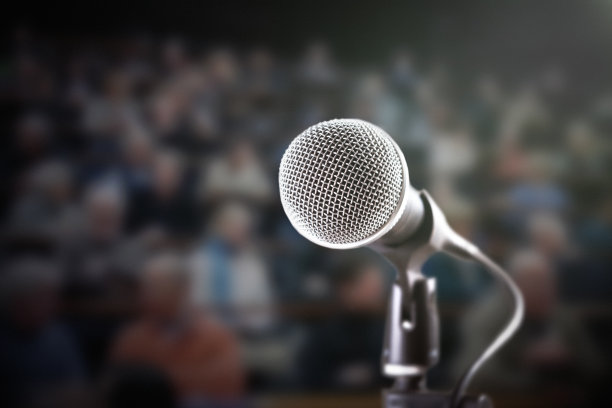 明亮的麦克风与黑暗，散焦观众在背景图片下载