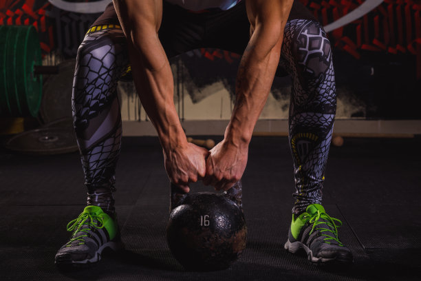 一个男人是运动员，他蹲着试图举起一个重物。图片下载