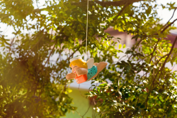 五彩天使陶瓷娃娃挂在花园里。图片下载