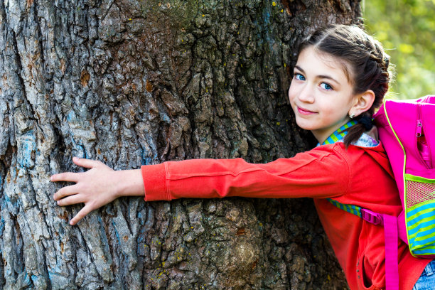 小女孩抱着一棵大树的树干图片下载
