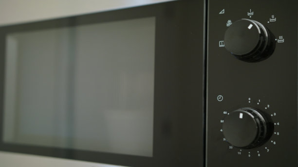 从微波炉中拿出一个容器的手素材图片