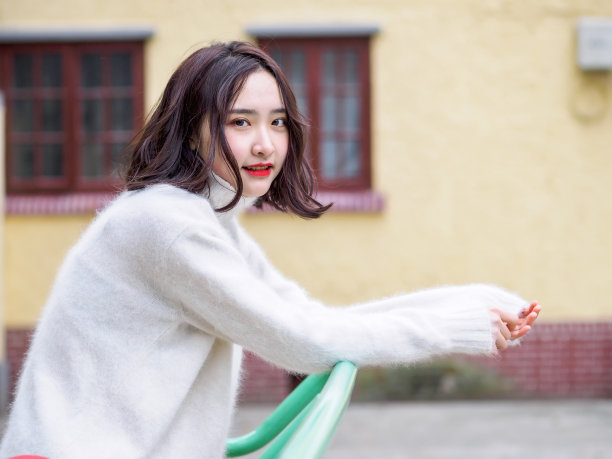 在模糊的房屋背景下，看向镜头的年轻棕发女子素材图片