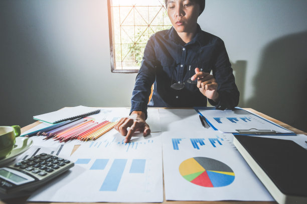 启动业务。亚洲设计师拿着笔工作指着讨论经济和工作的图表上下。有选择性的重点图片下载