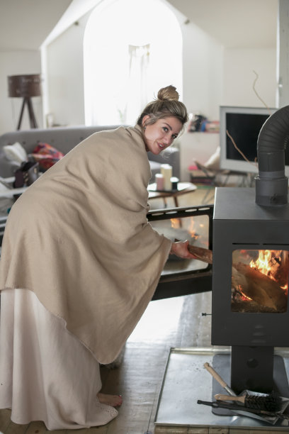 一位美丽的中年妇女将原木插入壁炉图片下载