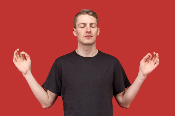 一个年轻男子的工作室肖像与一种平静感和内心的平衡放松和沉思。双手高举，以禅的符号分开两边。图片下载