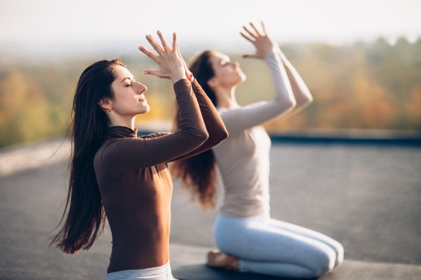 两个年轻漂亮的女人在室外屋顶上做瑜伽体式图片下载