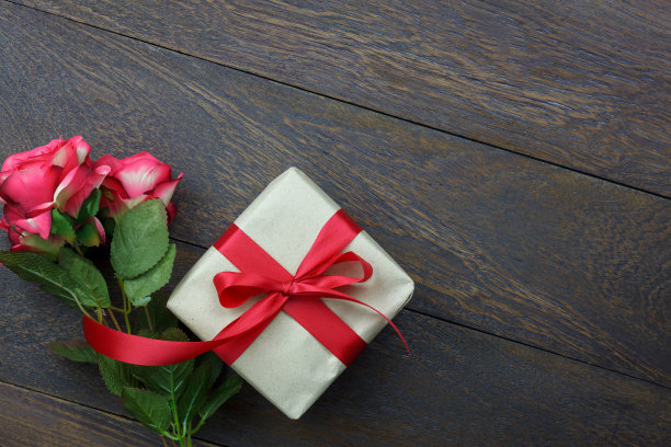 桌面视图图片装饰情人节背景概念。平铺红玫瑰和必要的象征爱的季节与礼盒在现代乡村棕色木制的家庭办公书桌工作室。图片下载