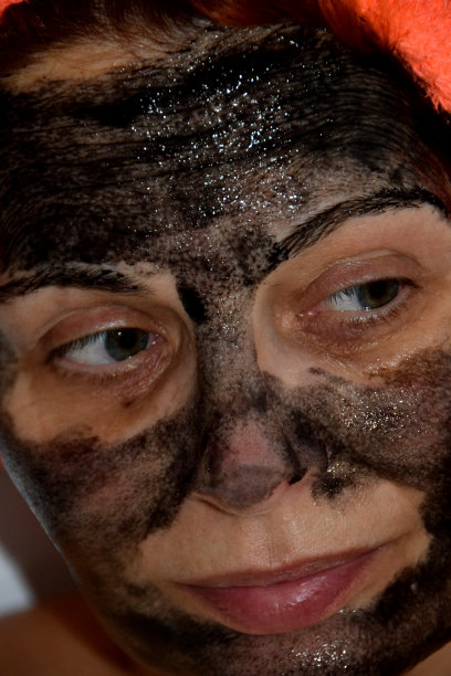 一位头上裹着橙色毛巾的女士脸上戴着黑色的化妆面具图片下载